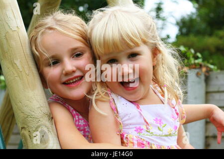 Foto ritratto bionda sorelle figli avvolgente seduta bionda bambini Giardino, amore familiare concetto, gioia concetto, sisterly amore stare insieme collegato Foto Stock