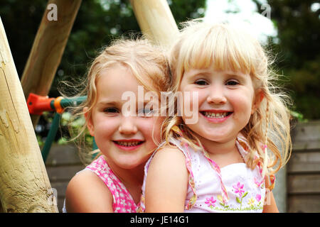 Foto ritratto bionda sorelle figli avvolgente seduta bionda bambini Giardino, amore familiare concetto, gioia concetto, sisterly amore stare insieme collegato Foto Stock