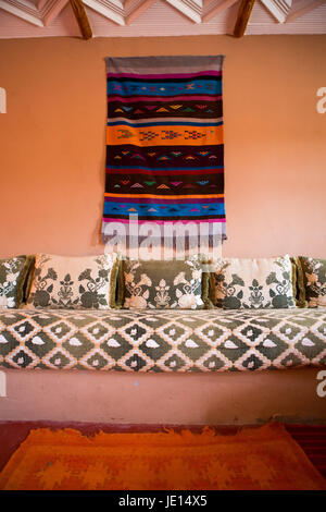 Tessuti colorati e arredi tradizionali in classico interno marocchino. Foto Stock