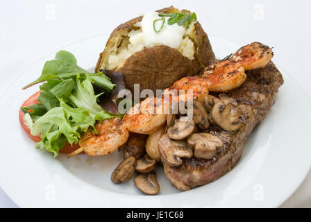 Cena gourmet di bistecca grigliata di gamberi, funghi, caricato di patate al forno e verdure miste leggera profondità di campo Foto Stock