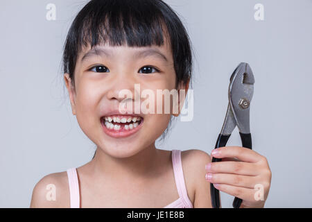 Cinese asiatici bambina pinze di trattenimento e mostrando il divario negli isolati di sfondo bianco Foto Stock