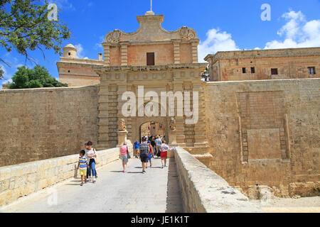 I turisti a piedi oltre il fossato bridge attraverso il portale di ingresso della città medievale di Mdina, Malta Foto Stock