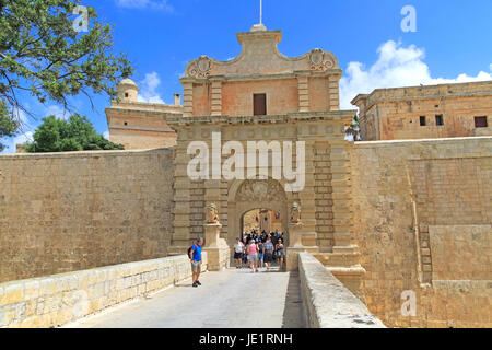 I turisti a piedi oltre il fossato bridge attraverso il portale di ingresso della città medievale di Mdina, Malta Foto Stock