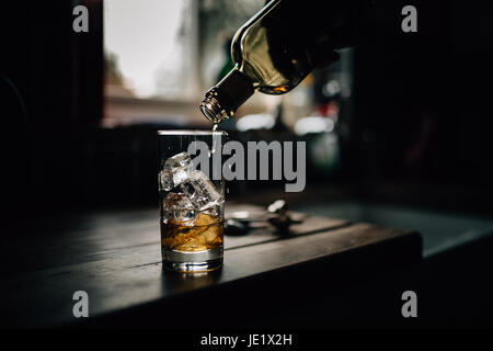 Whisky che viene versato in un bicchiere di vetro. Le bevande alcoliche e le bevande foto di Paulo Santos. Foto Stock