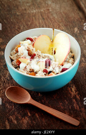 Fette di frutta con yogurt con il mestolo di legno sul lato posto sul recipiente posto sul tavolo di legno. Foto Stock