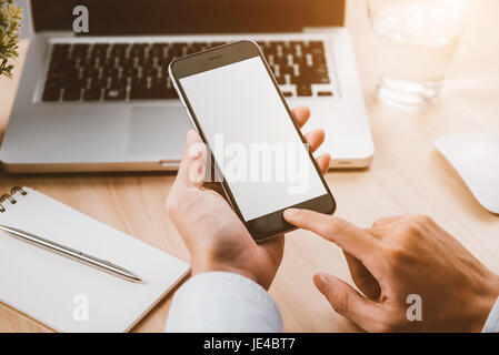 Imprenditore mano che tiene un telefono con schermo isolato sopra la scrivania in ufficio Foto Stock