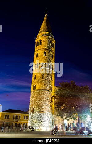 Illuminata torre campanaria sulla piazza Piazza d'uomo' con la folla di gente e bellissimi colori per il cielo di notte. Caorle, Italia. Foto Stock