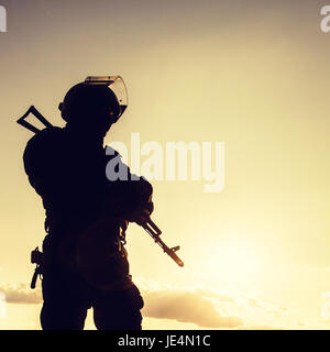 Silhouette di un funzionario di polizia con armi al tramonto Foto Stock