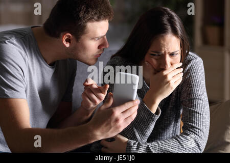 Il mio ragazzo per chiedere una spiegazione alla sua triste cheater ragazza seduta su un divano nel soggiorno in una casa interno con uno sfondo scuro Foto Stock