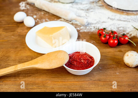 Diversi ingredienti per pizza, pasta di pomodoro e formaggio sul tavolo in legno Foto Stock