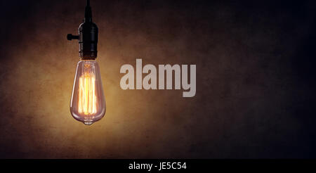 Vintage Hanging Light Bulb Over Dark Wall Foto Stock