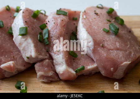 Materie carni fresche bovine filetto di maiale pronto per la cottura con roba verde su legno close up Foto Stock