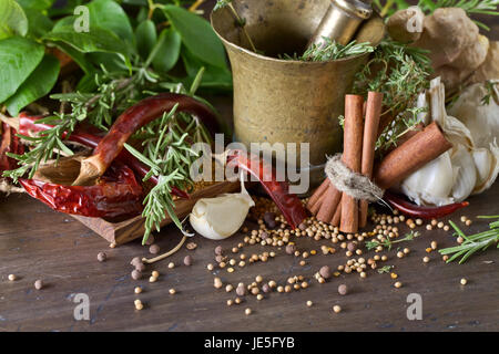 Diverse erbe e spezie su di un tavolo di legno . Rame antico mortaio con spezie . Foto Stock