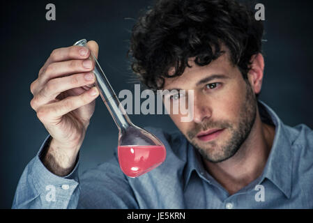 Uomo che guarda un liquido nel matraccio conico Foto Stock