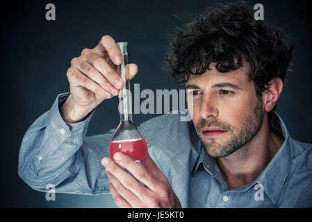 Uomo che guarda un liquido nel matraccio conico Foto Stock