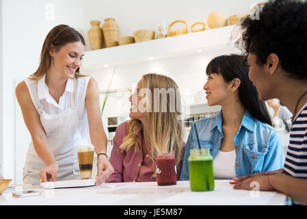 La cameriera che serve drinks per donne in cafe Foto Stock