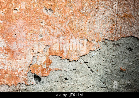 Una superficie in calcestruzzo con i resti di vernice di colore arancione e bianco candido e in parte caduto intonaco. Foto Stock