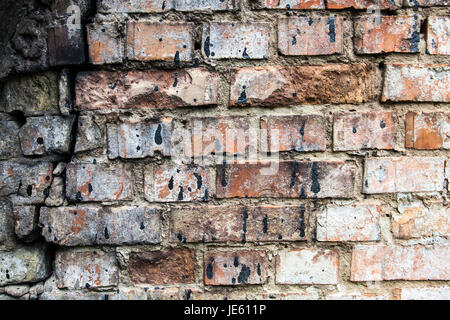 Il vecchio incrinato un muro di mattoni colorati di nero catrame. Foto Stock