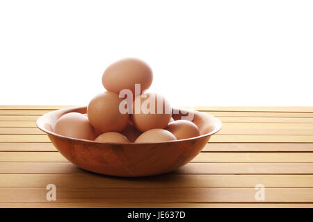 Le uova in una terrina su sfondo di legno Foto Stock