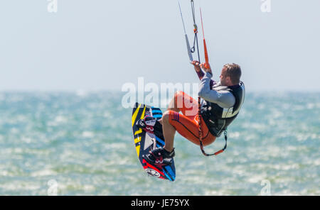 Il kitesurfing. Kitesurfer volare in aria come egli fa uno stunt mentre in mare in una giornata di vento. Foto Stock