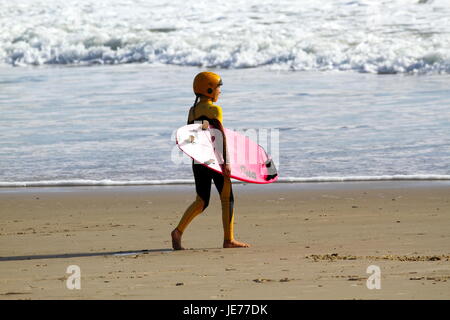 Un giovane preteen surfer girl andando a navigare. Foto Stock