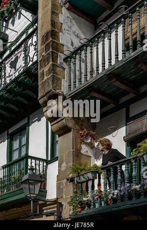 Donna sul balcone con fiori in un tipico Hondarribia (Fuenterrabia) Casa di Guipuzcoa, Paesi Baschi, Spagna, Europa Foto Stock