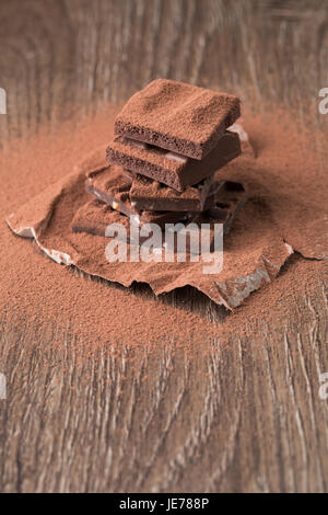 Piramide di cioccolato al latte, spruzzata con cacao in polvere sul tavolo di legno Foto Stock