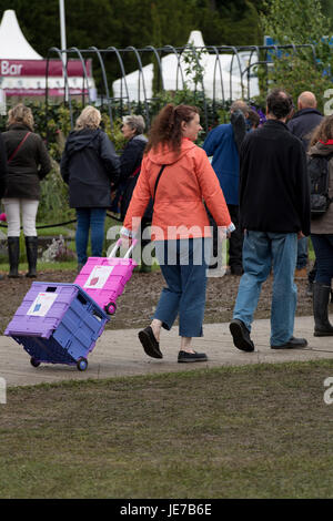 Persone che camminano e 1 donna che tira carrelli luminosi e pieghevoli per la spesa - First RHS Chatsworth Flower Show, Chatsworth House, Derbyshire, Inghilterra, Regno Unito. Foto Stock