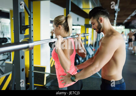 Donna facendo squat con il suo personal trainer Foto Stock