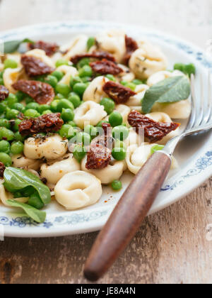 Tortellini con fresco giardino di piselli e pomodori secchi Foto Stock