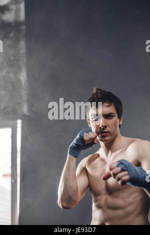 Boxer forte sotto i raggi del sole e la formazione di fumo mani con avvolgimenti di inscatolamento Foto Stock