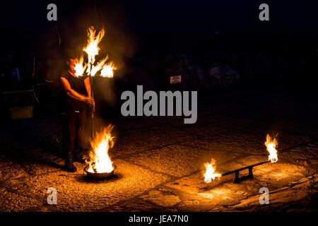 L'artista di strada con un bastone di masterizzazione e gli occhi chiusi si prepara a presentare il suo spettacolo di fuoco Foto Stock