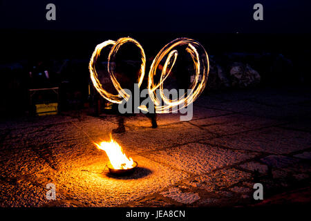 L'artista di strada con un ardente stick durante il suo pericoloso incendio visualizza Foto Stock