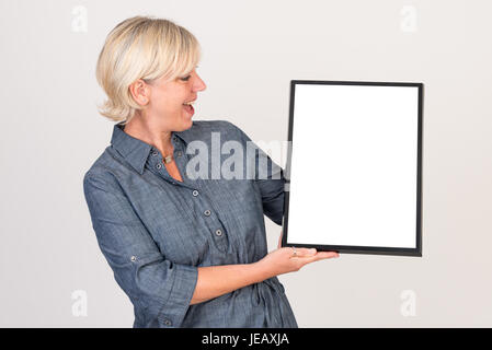 Bella medio europeo di età della donna in abiti aziendali tenendo un vuoto scheda bianca - studio shot davanti a uno sfondo bianco Foto Stock
