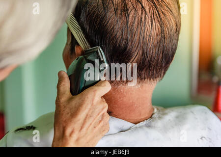 Hair stylist senior di taglio uomo asiatico di capelli grigi Foto Stock