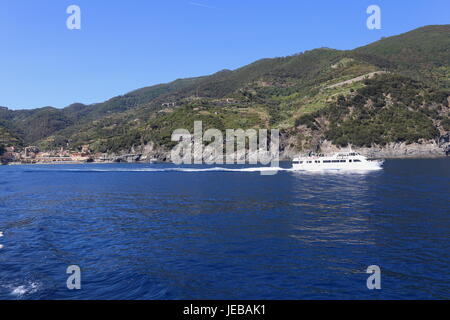 Imbarcazione turistica lasciando Monterosso e che si muove in basso lungo la costa tra i borghi delle Cinque Terre in Italia. Foto Stock