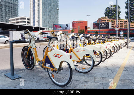 Milano, Italia - 11 Giugno 2017: noleggio biciclette parcheggiate sulla strada. Una serie di bici visto in prospettiva. Foto Stock