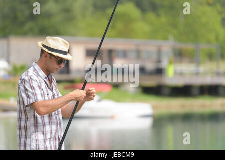 Uomo vicino al lago si prepara per la pesca Foto Stock