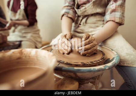 Close up bambino mani lavorando sulla ruota di ceramiche in officina Foto Stock