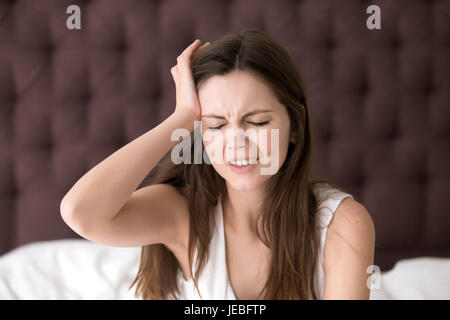 Donna nel letto che soffrono di mal di testa in mattinata Foto Stock