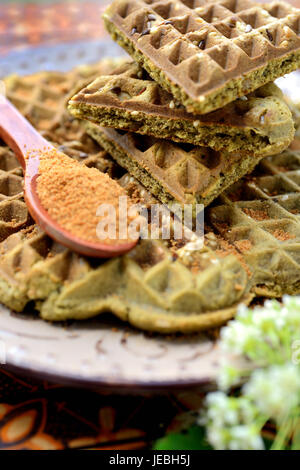 Waffles fatti in casa con aggiunta di matcha, pistacchi semi di lino. Decorata con zucchero di cocco. Foto Stock