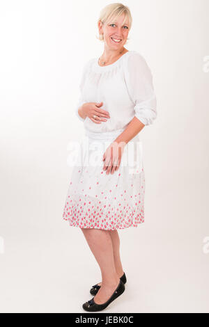 Ritratto di un attraente dai capelli biondi metà di età compresa tra unione donna che indossa abito bianco showin faccia felice - corpo pieno - studio shot su sfondo bianco Foto Stock