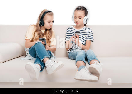 Cute ragazze utilizzando gli smartphone, ascoltare musica mentre è seduto sul lettino Foto Stock