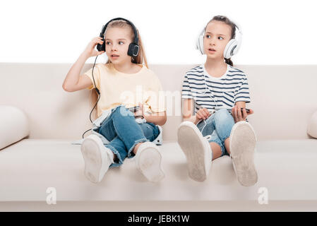 Cute ragazze utilizzando gli smartphone, ascoltare musica mentre è seduto sul lettino Foto Stock