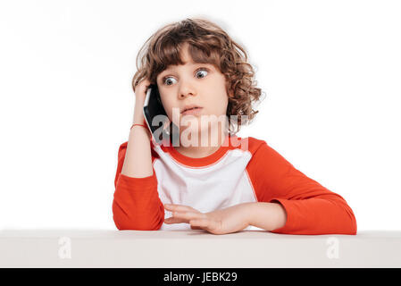 Carino piccolo ragazzo parlando da smartphone con espressione scioccato Foto Stock