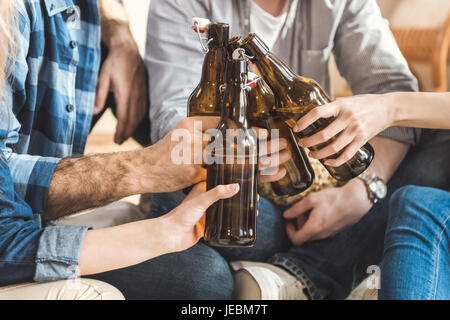 Immagine ritagliata di due giovani coppie tintinnio di bottiglie di birra Foto Stock