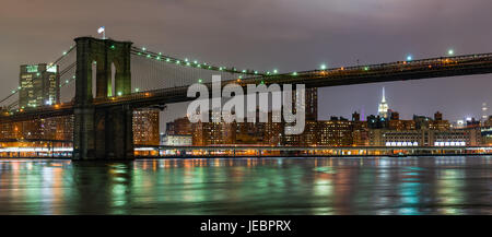 Il Ponte di Brooklyn e Empire State Building Panorama di notte con East River in primo piano, New York Foto Stock