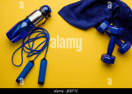 Varie attrezzature sportive e asciugamano isolato su giallo Foto Stock