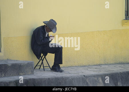 Honduras, Santa Rosa de Copán, casa di mura difensive, uomo, cura, sedersi, nessun modello di rilascio, America Centrale e America Latina, luogo, villaggio di montagna, persona, cowboy, stetson, cura, copricapo, sigarette, tabacco, sedia pieghevole, mura difensive, copia square, solitudine, solo, Foto Stock