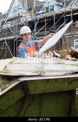 Builder sul sito di mettere i rifiuti nel cassonetto Foto Stock